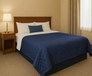 a bedroom with a blue and white bed and a night stand at Oshawa Inn Motel in Oshawa