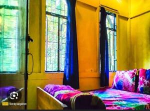 a bedroom with a bed and two windows at Andy homestay in Mawlynnong