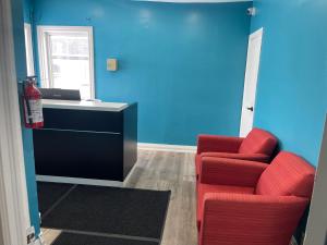 a living room with two red chairs and a desk at Oshawa Inn Motel in Oshawa