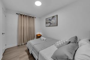 a white bedroom with a bed and a window at Poolside Paradise minutes away from the Falls in Thorold