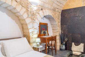 a bedroom with a bed and a desk in a stone wall at Dammuso 3cirniechi in Ragusa