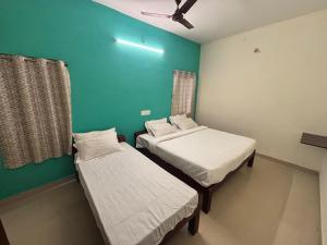 a room with two beds and a green wall at Thamira Residency Yercaud in Yercaud