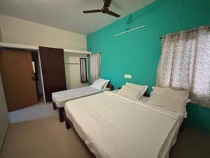 two beds in a room with a green wall at Thamira Residency Yercaud in Yercaud