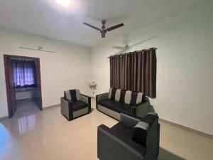 a living room with two chairs and a ceiling fan at Thamira Residency Yercaud in Yercaud