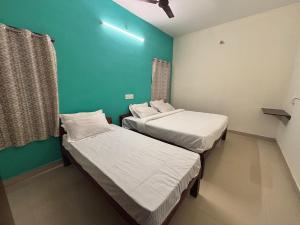 two beds in a room with a green wall at Thamira Residency Yercaud in Yercaud