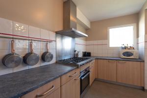 a kitchen with wooden cabinets and a stove top oven at Gite Le Bérierot avec piscine in Ouzous