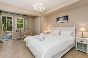 a bedroom with a large white bed and a chandelier at Le Mas d'Aiguebelle in La Croix-Valmer +24 photos