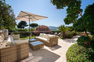 a patio with two couches and an umbrella at Le Mas d'Aiguebelle in La Croix-Valmer
