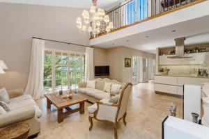 a living room with white furniture and a chandelier at Le Mas d'Aiguebelle in La Croix-Valmer