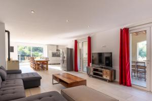a living room with red curtains and a television at Villa Luminières 2 in Sallelles