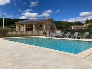 a swimming pool with chairs and a house at Villa Luminières 2 in Sallelles