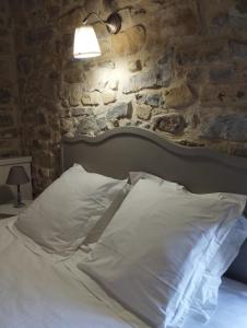 a bed with white pillows and a stone wall at Gîte SPA Sauna Piscine in Grospierres +27 photos