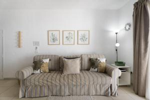 a living room with a striped couch with pillows at Serene Terrace And Pool in Playa de las Americas +20 photos