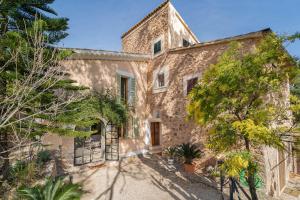 an exterior view of a stone house with trees at Se Taulera in Fornalutx