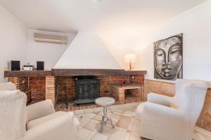 a living room with a brick fireplace and white chairs at Es Rafal in Santa Margalida