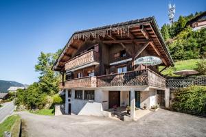 a house with a balcony and an umbrella at Chalet Arnica in Morzine
