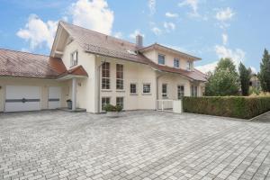 a large white house with a brick driveway at Ferienwohnung Welte in Meckenbeuren