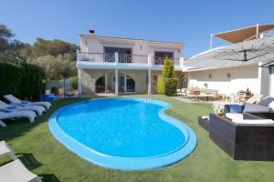 a villa with a swimming pool in front of a house at Tres Palmeras in Calas de Mallorca