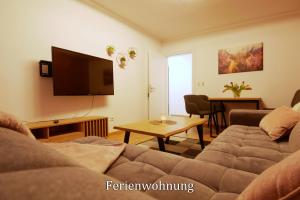 a living room with a couch and a flat screen tv at Pension Haus Linden in Winterberg
