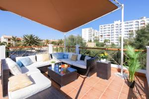 a patio with couches and tables on a balcony at Tres Palmeras in Calas de Mallorca