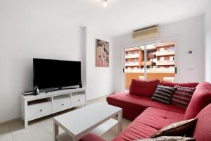 a living room with a red couch and a flat screen tv at Beach Front Apartment Puertito in Puertito de Güímar