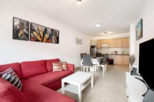 a living room with a red couch and a kitchen at Beach Front Apartment Puertito in Puertito de Güímar