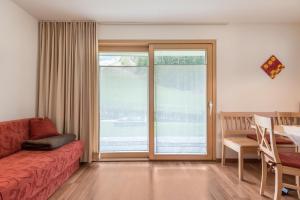 a living room with a red couch and a table and a glass door at Hilber Sass Rigais in Villnoss