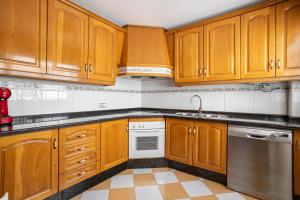 a kitchen with wooden cabinets and stainless steel appliances at Terraza Mar y Montaña in Nerja