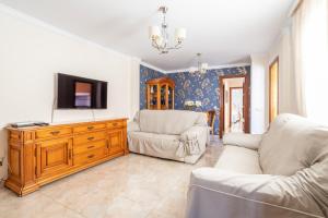 a living room with two chairs and a television on a wooden dresser at Terraza Mar y Montaña in Nerja