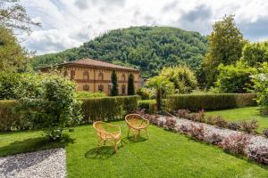 a garden with two chairs and a building at Villa Brecht in Bagni di Lucca