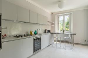 a white kitchen with a counter and stools in it at Villa Brecht in Bagni di Lucca