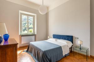 a bedroom with a blue bed and a window at Villa Brecht in Bagni di Lucca