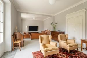 a living room with two chairs and a television at Villa Brecht in Bagni di Lucca