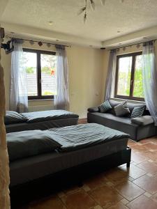 a bedroom with two beds and a couch and windows at Gemütliche Einliegerwohnung in Imsbach