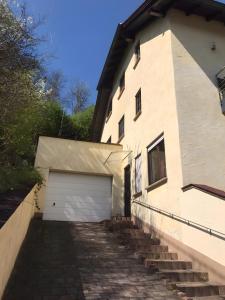 a white building with a garage and stairs at Gemütliche Einliegerwohnung in Imsbach +7 photos