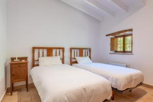two beds in a room with white walls and a window at Villa S'erisal in Alaró +20 photos