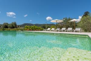a large swimming pool with chairs and umbrellas at Villa S'erisal in Alaró