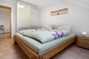 a bedroom with a bed with white sheets and purple flowers at Ferienwohnung Bella in Fuhlendorf