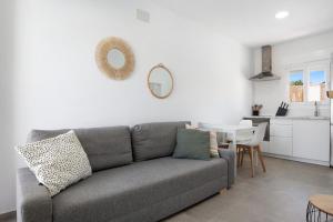 a living room with a gray couch and a kitchen at Casa Lavanda Vejer in La Muela