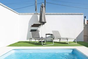a swimming pool with two chairs and an umbrella at Casa Lavanda Vejer in La Muela