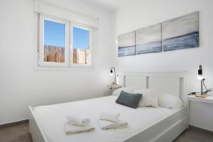 a white bedroom with a bed with two towels on it at Casa Lavanda Vejer in La Muela +17 photos