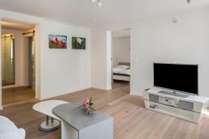 a white living room with a tv and a table at Ferienwohnung Feine Natur in Bahlingen