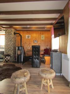 ein Wohnzimmer mit 2 Hockern und einem Herd in der Unterkunft Chalet "Chez Claudine et Charles" in Mase