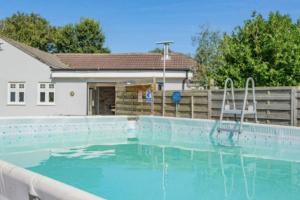 a swimming pool with a chair in front of a house at Adgestone Villa - A Luxurious Countryside Escape with Heated Pool, Near Sandown Beach, Dog Friendly in Rural Sandown - Perfect Getaway for Family & Friends in Alverstone