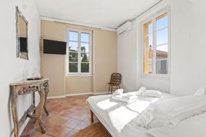 a bedroom with a bed and a table and two windows at L'Escale Au Soleil in Saint-Aygulf