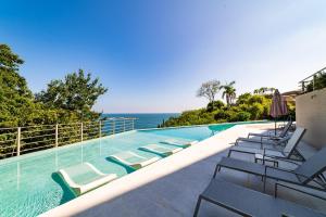 a swimming pool with lounge chairs and the ocean at 1083 - Cosmo 3A3 in Tangolunda