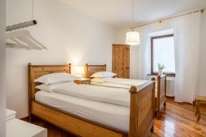 Zwei Betten in einem Schlafzimmer mit weißen Wänden und Holzboden in der Unterkunft Wunderhorn in Civezzano