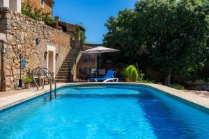 a swimming pool with a chair and an umbrella at Finca So na Sopa in Artá