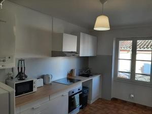 a kitchen with white cabinets and a microwave at Le beau 25 République in Montauban