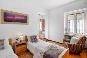 a white bedroom with a bed and a chair at Dimora Il Feudo - Predazzo in Predazzo